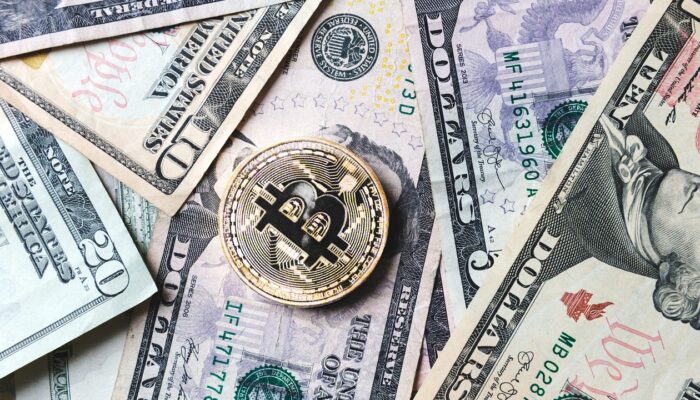 Pildil Ameerika dollarid ning bitcoini münt. Pilt illustreerib teemat: JPMorgan ja krüptoraha - uus partnerlus
